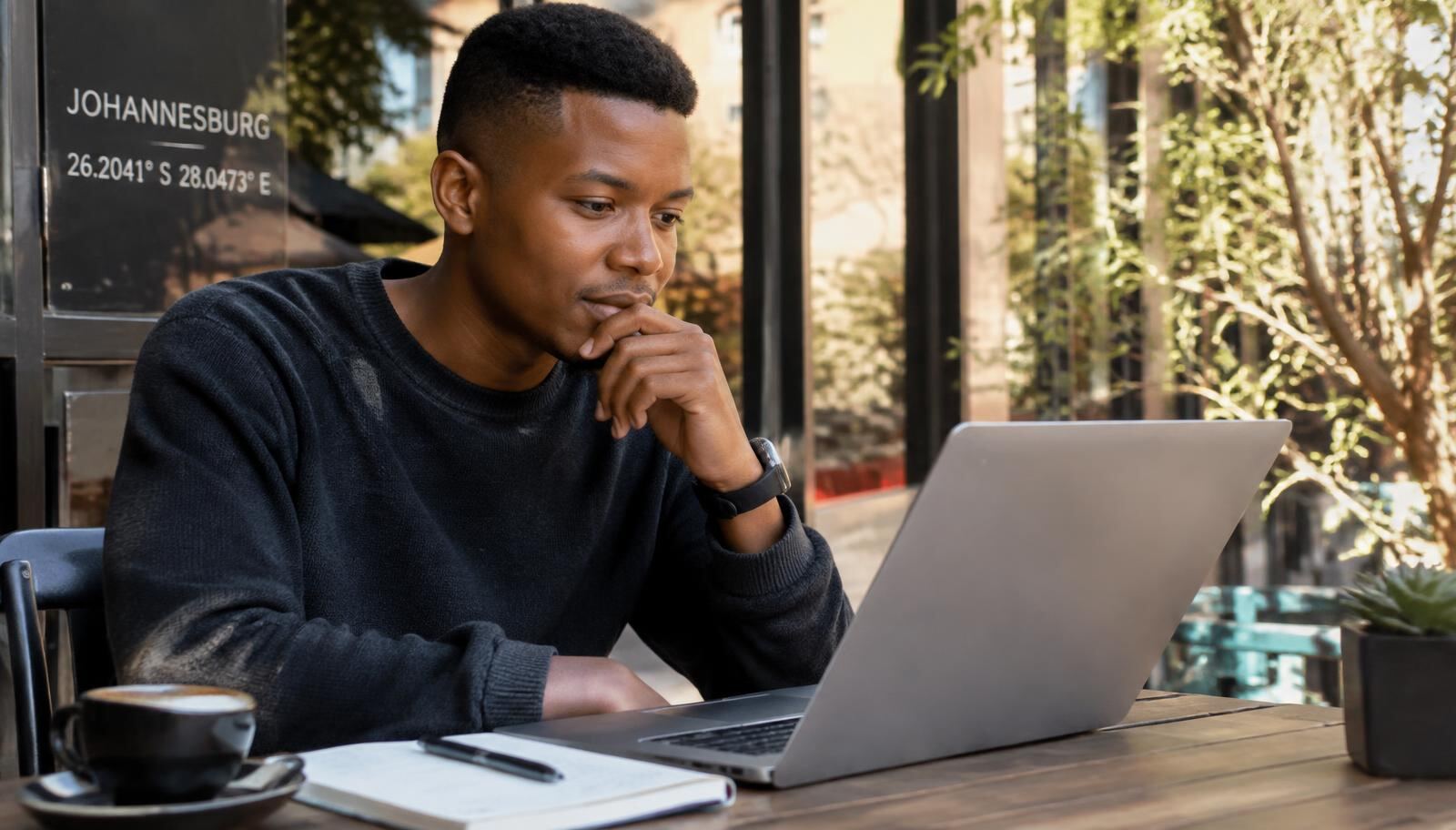 Man researching insurance questions on a laptop at a cafe